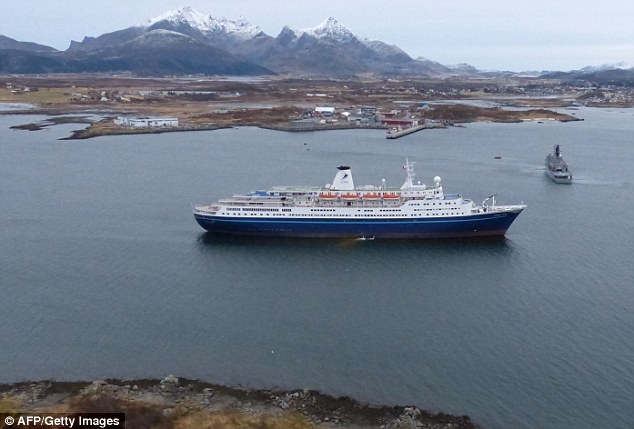 A handout photo released by the Royal Norwegian Air Force and taken from a rescue helicopter shows a Norwegian coast guard vessel in front of Bahamas-registered cruise liner Marco Polo