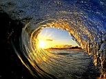 Early morning shot: Sun rays burst through the arc of a wave on the North Shore in Oahu, Hawaii in this photo snapped by travel photographer Clark Little