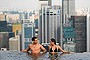 Models pose for photographers in the infinity pool of the Skypark that tops the Marina Bay Sands hotel towers in Singapore June 24, 2010. The Sands Skypark, which opened to the public on Thursday, features a 150-metre-long infinity pool overlooking Singapore's city skyline and Marina Bay, a public observation deck and a restaurant run by a celebrity chef. REUTERS/Vivek Prakash (SINGAPORE - Tags: BUSINESS SOCIETY CITYSCAPE TRAVEL)