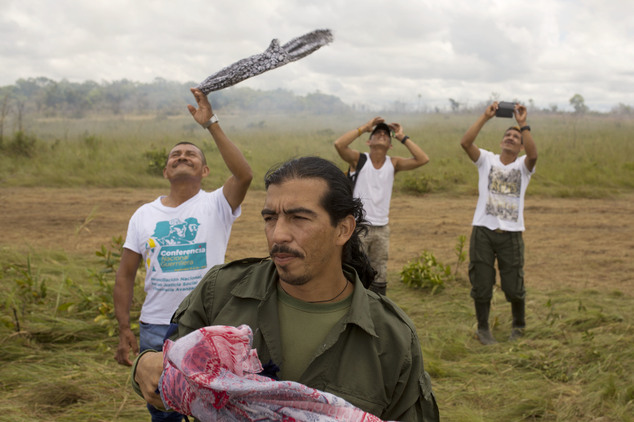 Rebels wave as a helicopter transporting rebel leaders of the Revolutionary Armed Forces of Colombia, FARC, takes off from Yari Plains, Colombia, Saturday, S...