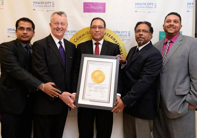 The recent Gold Seal of Approval award from the Joint Commission International brought smiles to executives connected to the facility.  Posing proudly with the award are (l. to r.) Health City Cayman Islands quality coordinator Vinit Raj; Ascension Executive Vice President John Doyle, Cayman Islands Premier Alden McLaughlin; Dr. Chandy Abraham, facility director and head of medical services at Health City; and Shomari Scott, Health City’s marketing director.
