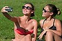 Two girls take a photograph of themselves on their mobile phone as they relax in the warm weather in Hyde Park on July 18, 2014 in London, England. The Met Office has issued a heatwave alert as temperatures soar to their highest of the year.