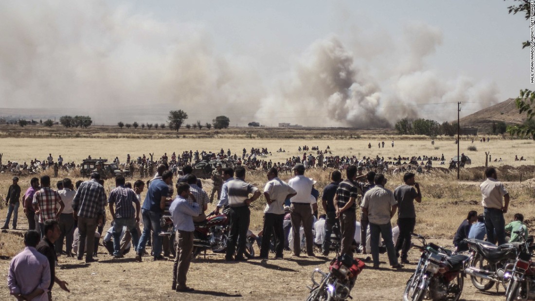 Syrians wait near the Turkish border during clashes between ISIS and Kurdish armed groups in Kobani, Syria, on Thursday, June 25. The photo was taken in Sanliurfa, Turkey. ISIS militants disguised as Kurdish security forces infiltrated Kobani on Thursday and killed quot;many civilians,quot; said a spokesman for the Kurds in Kobani.