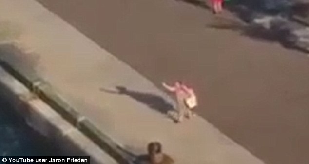 The mother gestures towards the ship before dropping to her knees and pleading for the crew to stop