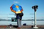 A woman holding an umbrella stands next to a pair of binoculars for tourists at the Imjingak pavilion near the demilitarized zone which separates the two Koreas, in Paju, north of Seoul.