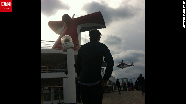Passengers aboard the disabled Carnival Triumph cruise ship wave to a helicopter overhead as it approaches the vessel on February 14. 