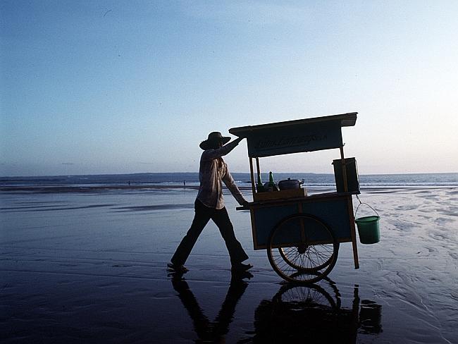 A street merchant wheels his cart along Kuta Beach in Bali.