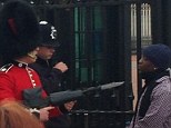 Tense encounter: A member of the Queen's Guard can be seen levelling his rifle, tipped with a bayonet, at the throat of a man in front of the gates of Buckingham Palace