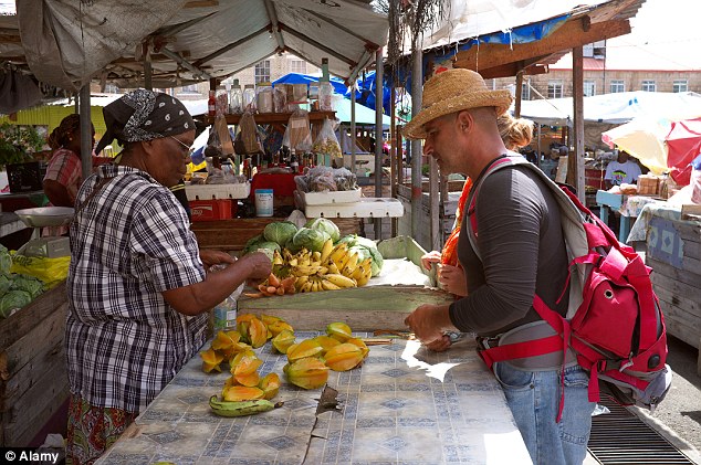A tourist makes a purchase at a fruit and vegetable market in Grenada, where some Brits have fallen ill