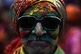 A man daubed in coloured powder poses for a picture at a temple during 