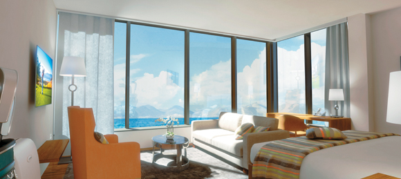 Seaview Junior Suite at The Reef by CuisinArt has a bedroom with seating area and panoramic windows that overlook either the golf course or the Caribbean Sea.